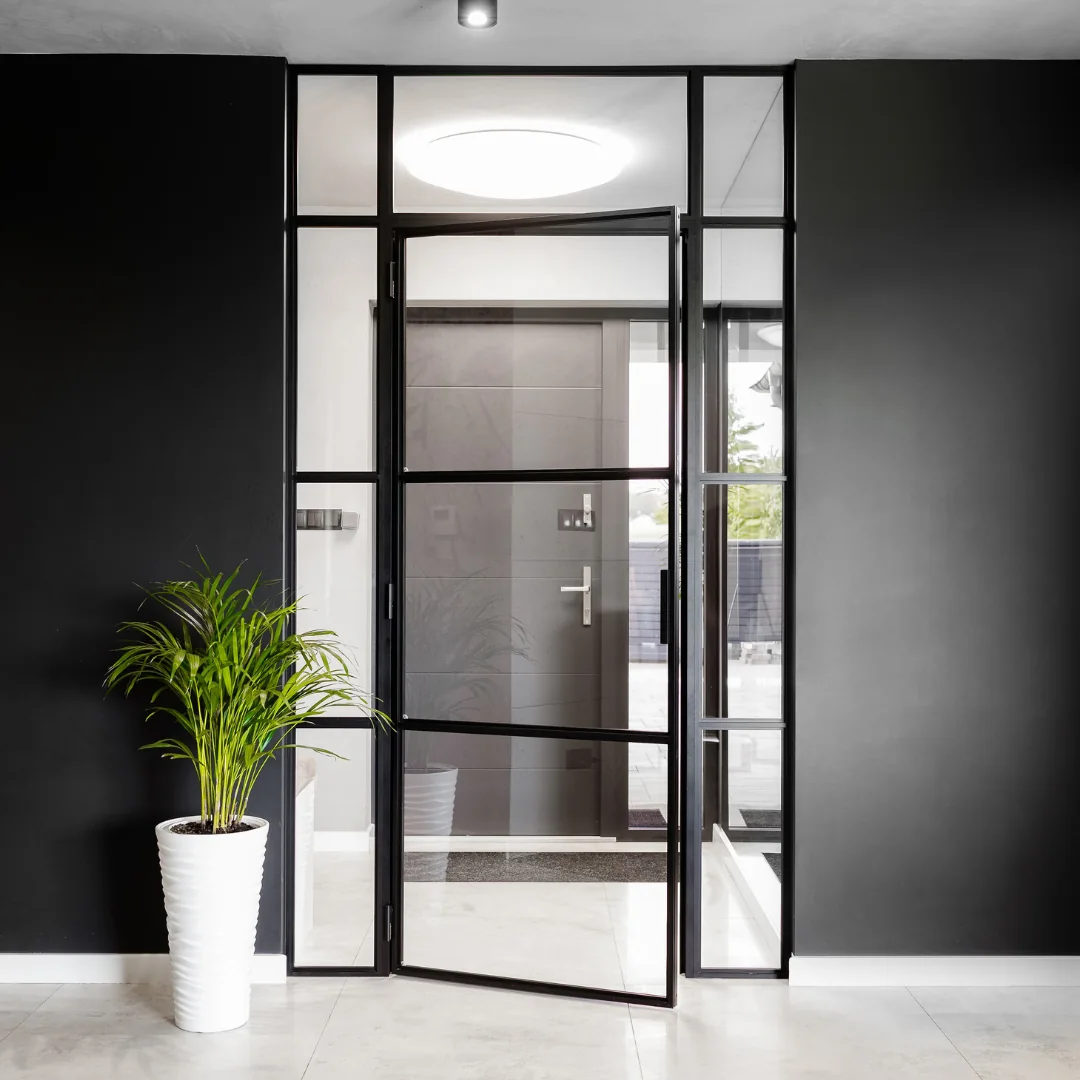 Black aluminium loft screen with a hinged door in a hallway with a black wall