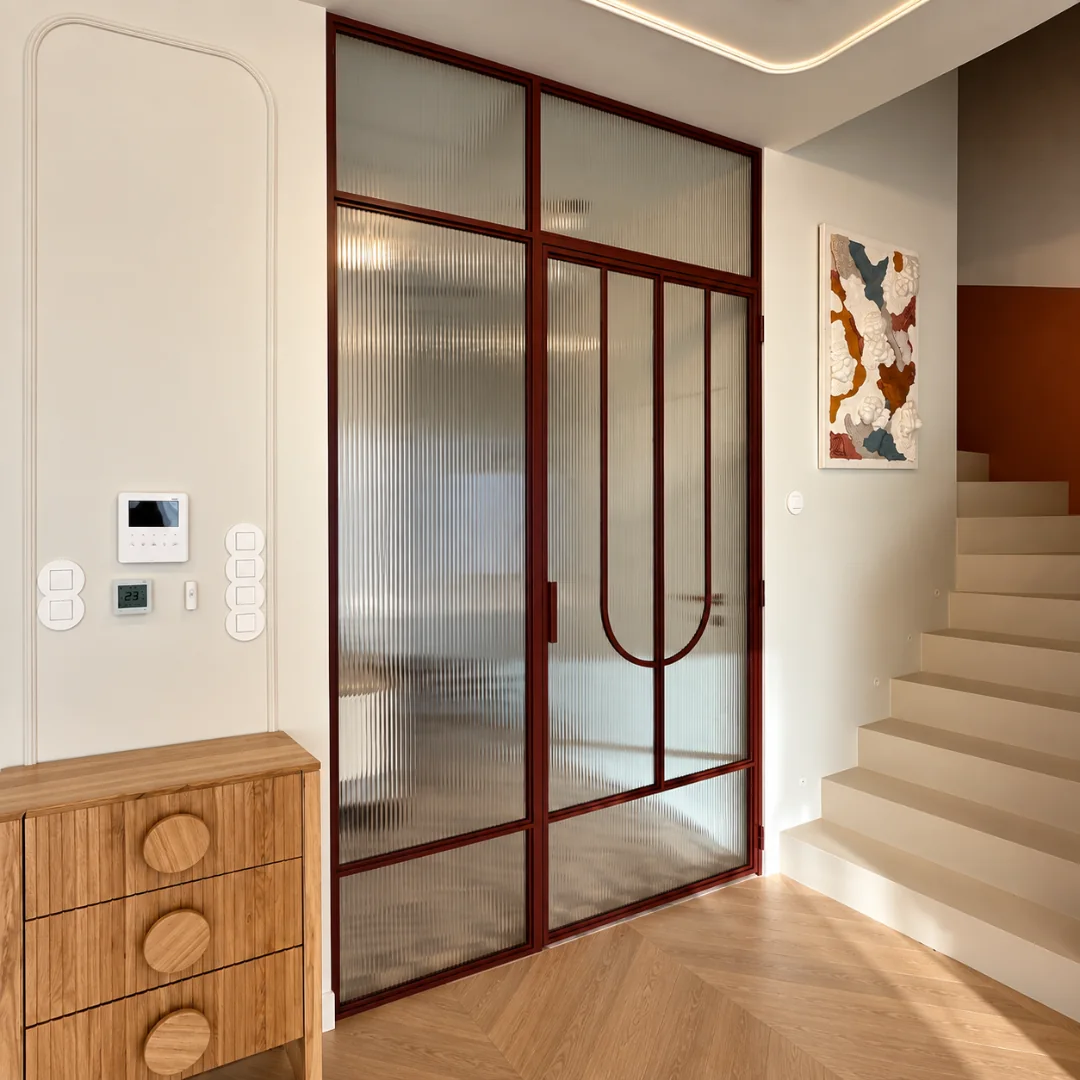 Burgundy loft partition with fluted glass and arched bars beside a staircase
