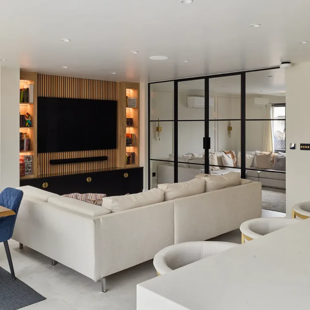 Black glazed loft partition behind the sofa in an open-plan living room
