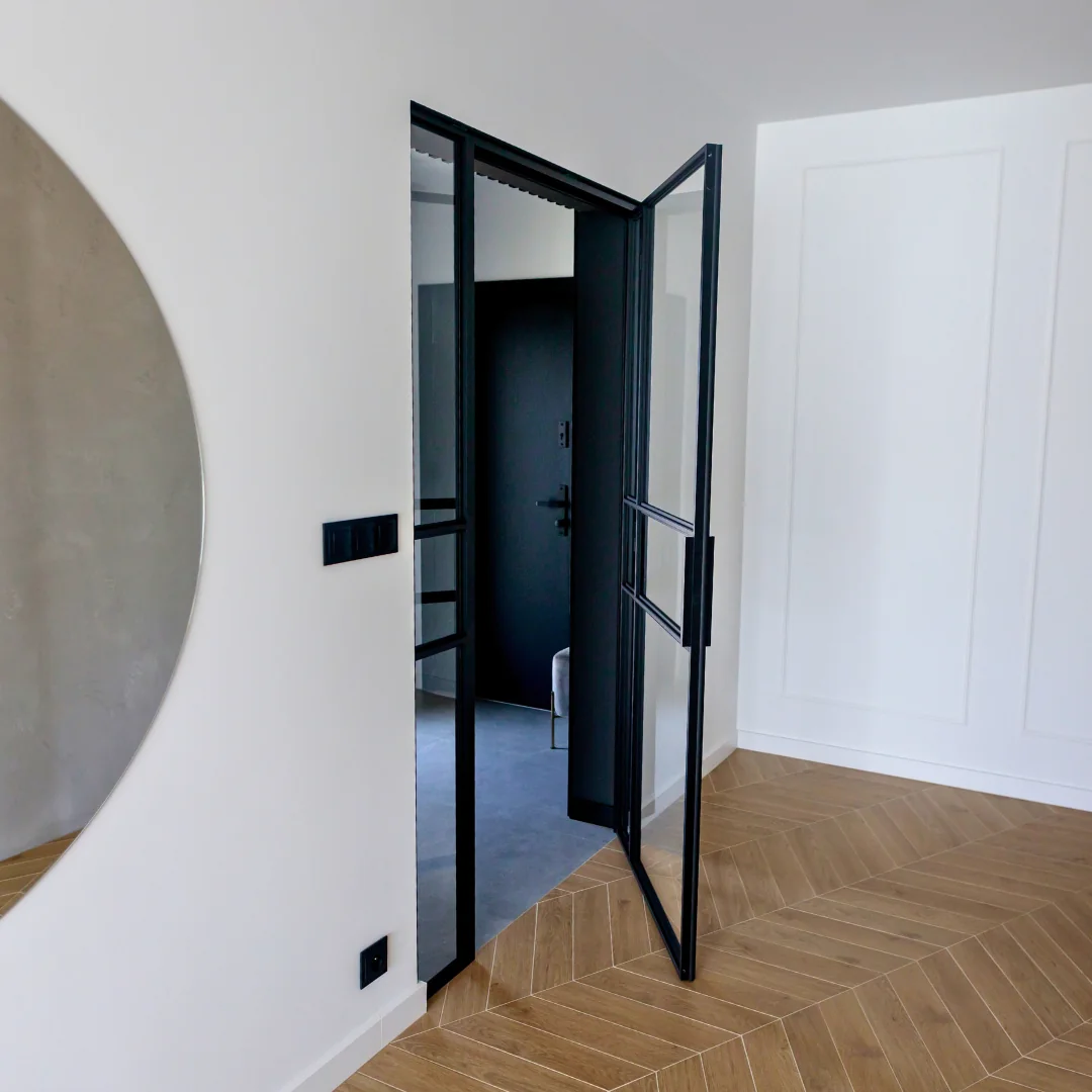 Open black hinged loft door in a white hallway with herringbone flooring